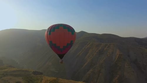 Panoramic View of Hot Air Balloon Flying Across the Sky in Mountain Landscape
