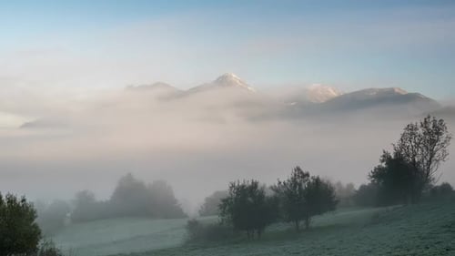 Foggy Clouds Moving in Alpine Mountains Valley at Sunrise Morning