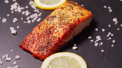 Delicious Baked Golden Salmon on a Black Plate in the Kitchen