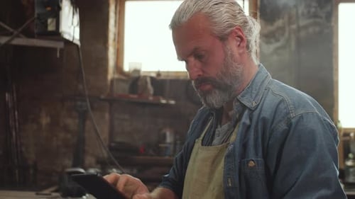 Adult Man Using Tablet in an Industrial Workshop