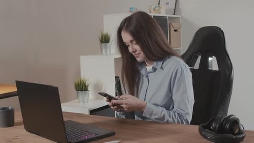 Young Woman Using Phone While Sitting at Desk
