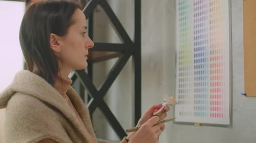 Woman Comparing Color Swatches in Modern Workplace