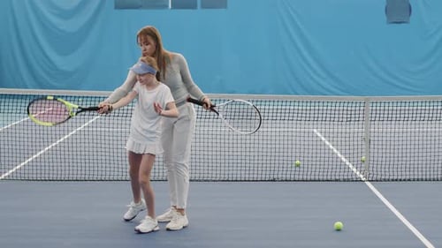 Child Receives Tennis Coaching on Indoor Court