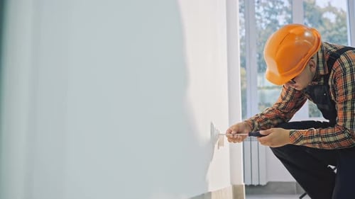 Construction Worker Uses Screwdriver on Electrical Outlet
