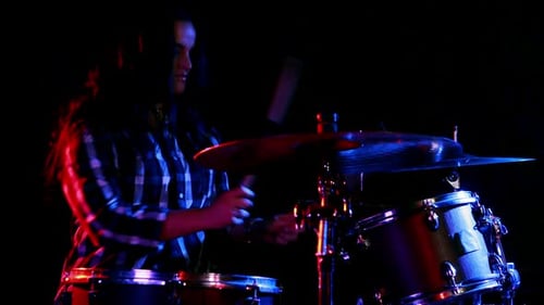 Female Drummer Performing in Dark, Colorful Setting