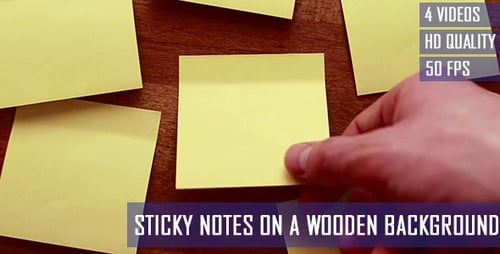 Hand Places Sticky Note on Wooden Background