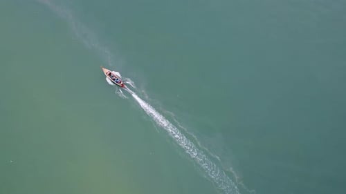 Aerial view from a drone of Thai traditional longtail fishing boats sailing in the sea.