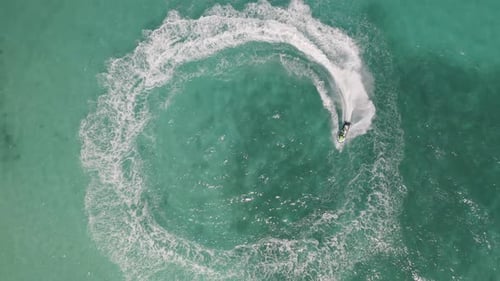 Aerial top view of jet ski or boat drawing a shape on sea ocean turquoise water. Adventure