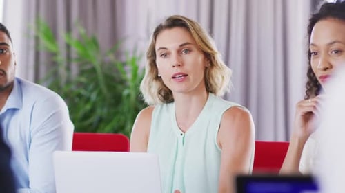 Professional businesswoman talking to her colleagues while sitting in modern office in slow motion