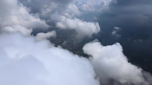 Aerial View From Airplane Window at High Altitude of Distant City Covered with Puffy Cumulus Clouds