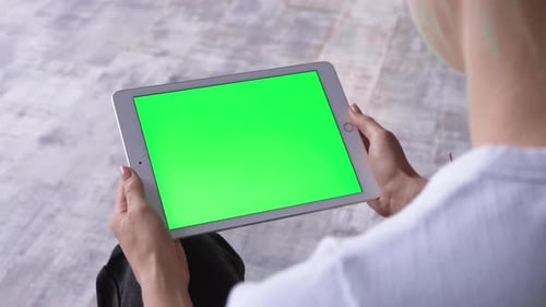 View over shoulder on tablet device in hands of Caucasian woman. Female holding computer