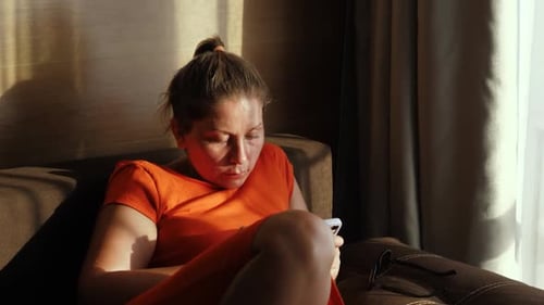 Woman Relaxing on Couch Using Smartphone