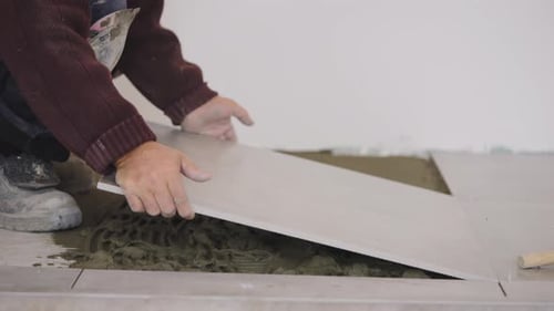 Man Installing Floor Tiles in Home