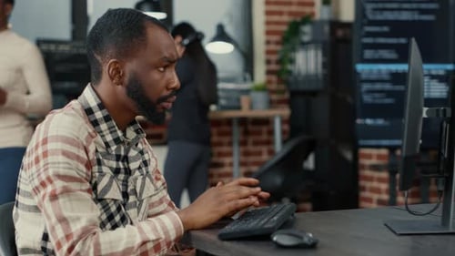 Tripod Shot of African American Cloud Programer Writing Code Focused Looking at Computer Screen
