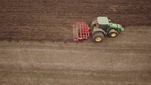 a Large Tractor Plows a Field