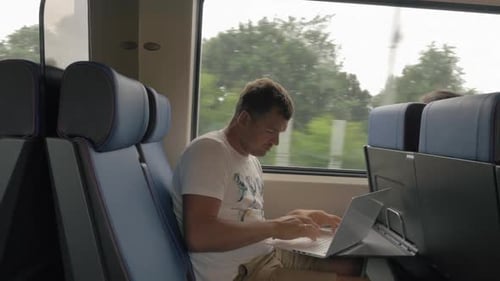 Mann benutzt Laptop während der Fahrt im Nahverkehrszug