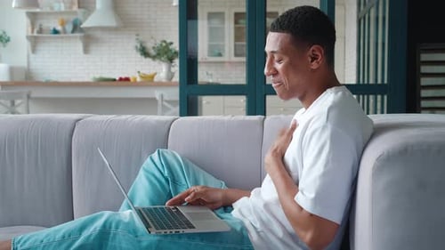 Man Relaxing on Couch Video Calling on Laptop