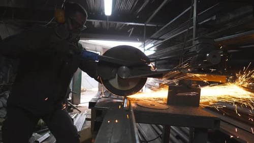 Industrial Worker Cuts Metal Bar with Sparks