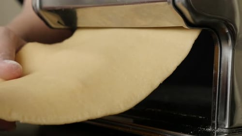 Dough being rolled through a pasta machine
