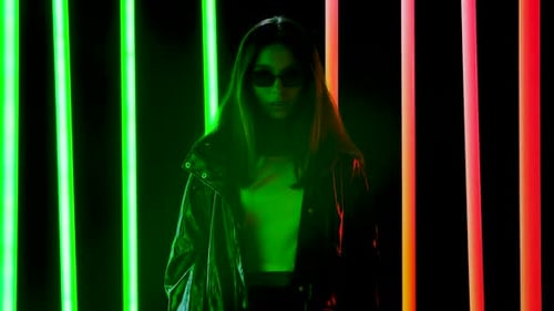 Stylish Woman in Shiny Jacket Stands Near Neon Lights