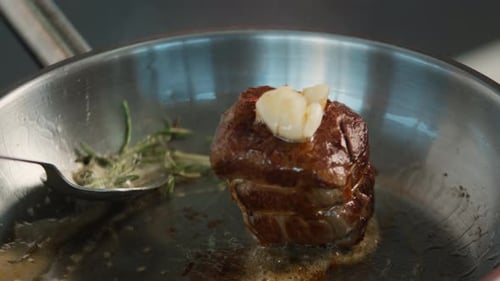 Close-up of a filet mignon being cooked in a frying pan