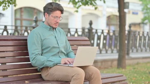 Man Thinking while using Laptop on Bench Outdoor