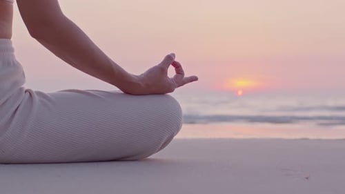 Femme asiatique est assise au front de plage, pose comme si elle méditait