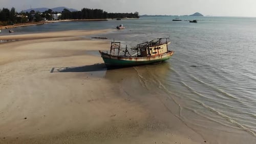 Fischerschiff an der Sandküste in der Nähe von Wasser. Altes verlassenes rostiges Fischerboot am Sandstrand in der Nähe von Meer