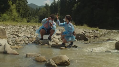 Diverse Multiethnic Scientists in Protective Uniforms Examining Water Samples From Polluted Mountain