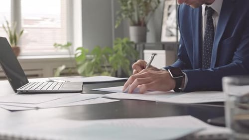 Professional Man Signs Documents at Desk