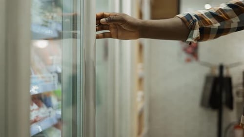 A Shopper Selects Food in the Fridge of a Grocery Store