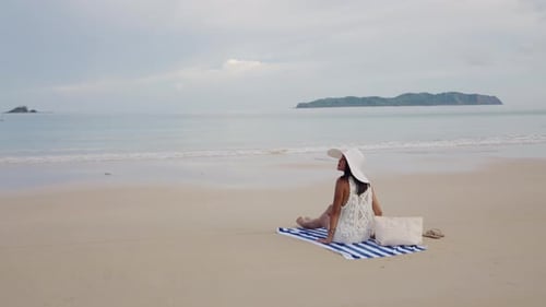 Junge Frau entspannt sich auf einem Strandtuch mit Blick auf das Meer