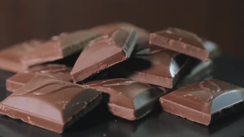 Delicious Dark Chocolate Chunks Rotating on Black Surface