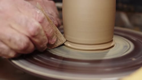 Potter utilise le tour de potier et le façonne avec un grattoir