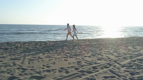 Aerial View of Couple Having Fun Running Along the Beach Near the Water