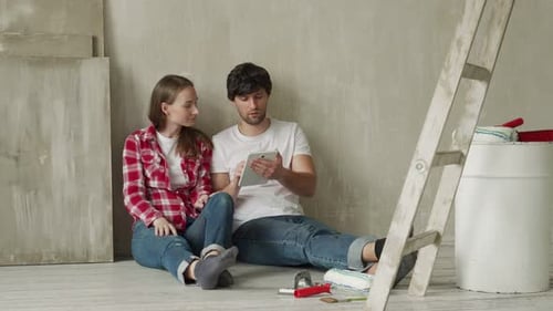 Pareja familiar usando tableta digital durante la renovación de una casa nueva