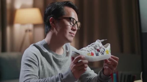 Close Up Of Asian Male Footwear Designer Holding And Looking At The Colourful Pattern Sneakers