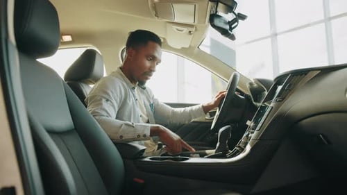 Handsome Young African Man in Denim Shirt Pressing Touchscreen on Car Multimedia