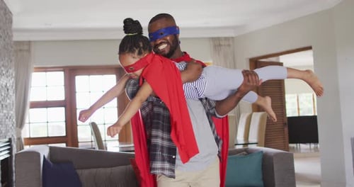 Dad and Daughter Playing Superhero Together at Home