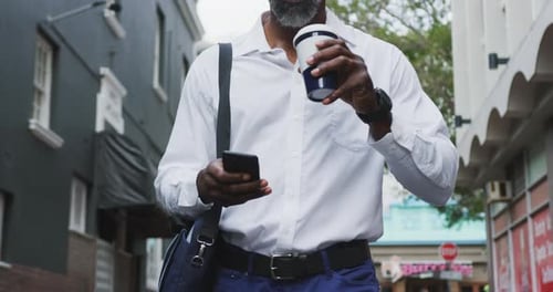 Man Drinking Coffee and Using Phone in City