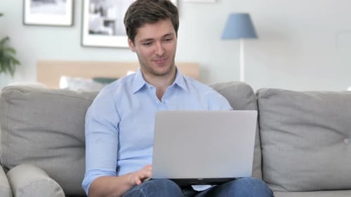 Smiling Young Adult Man Video Conferencing on Laptop