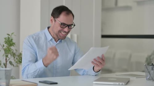 Man Reads Document and Reacts With Joy