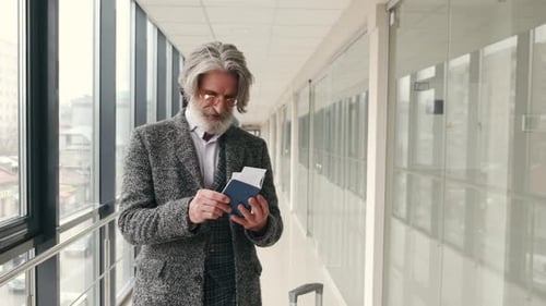Elegant Senior Man Checking Passport and Bording Pass at Corridor in the Airport