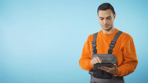 Repairman Working on Tablet Agains Light Blue Background