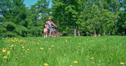 Couple Riding Tandem Bicycle Through Sunny Park
