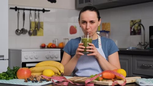 Woman in Apron Enjoying Healthy Green Smoothie