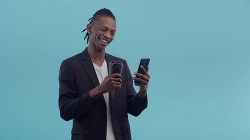 Young Adult Using Smartphone and Holding Drink