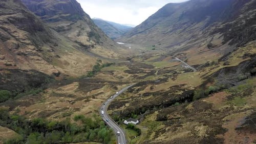 Aerial view of a valley in the Highlands with a road that winds through the m