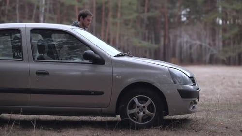 Man get out of the car and opens the hood.
