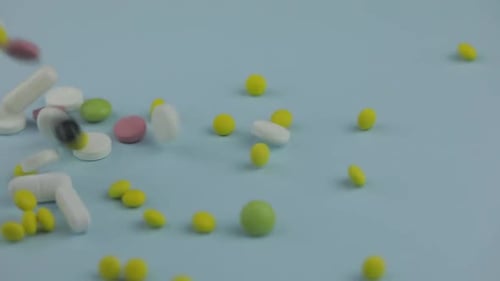 Colorful Pills Falling on Light Blue Surface